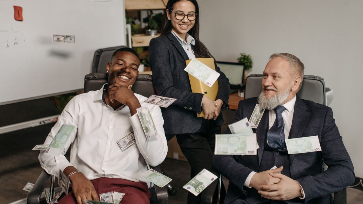 Office scene of diverse business professionals with money scattered, creating a playful environment.