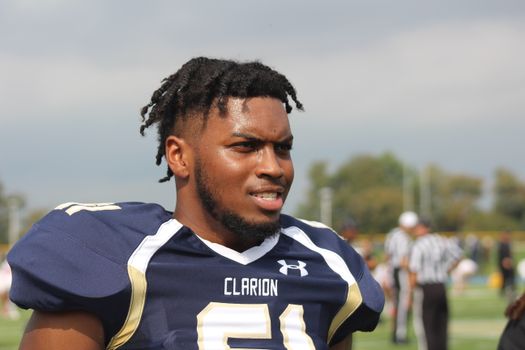 Portrait of a determined football player wearing a Clarion jersey on the field.