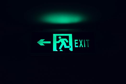 A glowing green exit sign with an arrow, guiding direction in low light.
