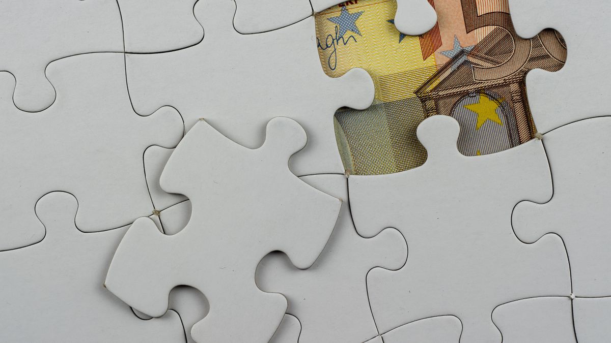 Close-up of a jigsaw puzzle missing piece revealing Euro currency underneath.