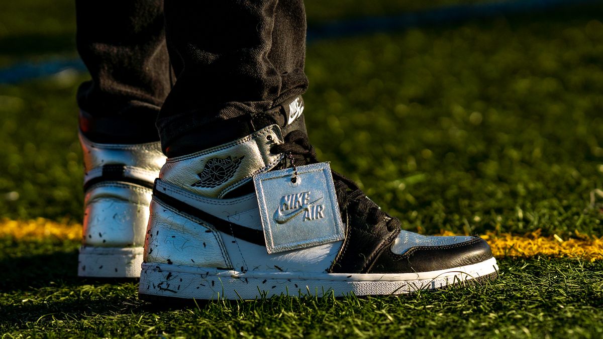 Close-up of black and white sneakers with Nike Air tag on green grass field.