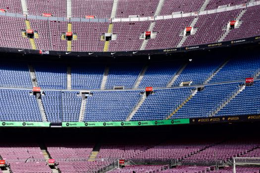 Wide-angle view of the empty stands at Camp Nou Stadium in Barcelona displaying vibrant seat colors.