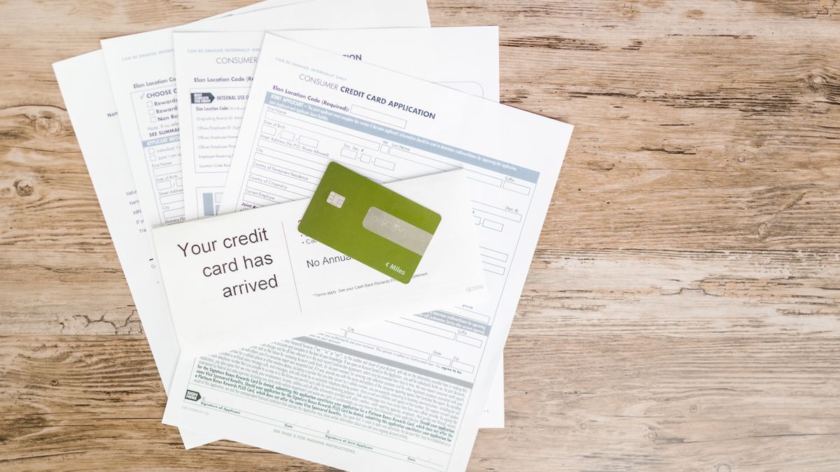 Top view of credit card and application documents on wooden surface.