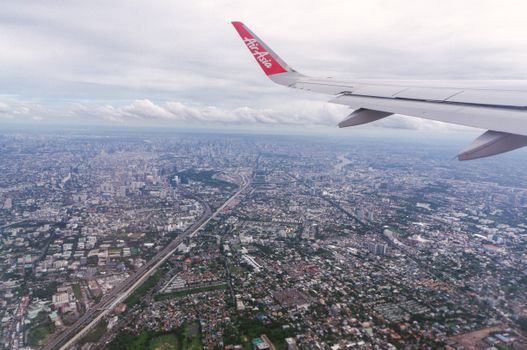 Scenic aerial view of Bangkok cityscape from an airplane window at daytime, showcasing urban sprawl.