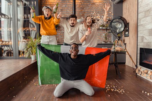 Four friends celebrate indoors with popcorn and flags, enjoying a leisure moment.