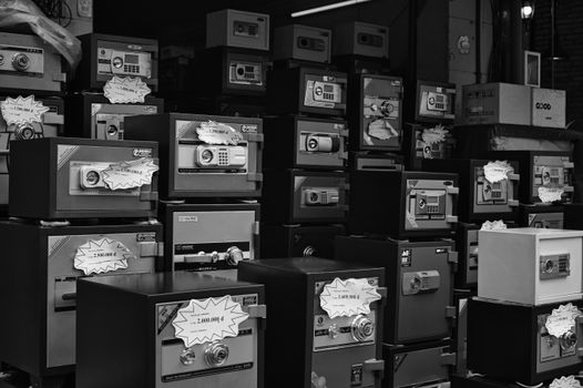Monochrome photo of stacked safes with price tags in a store setting.