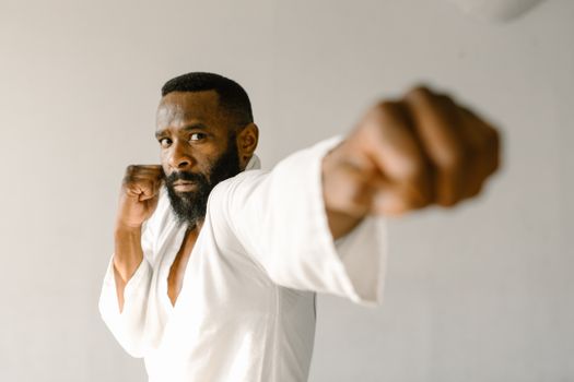 Martial artist demonstrating a powerful punch in a traditional karate uniform indoors.