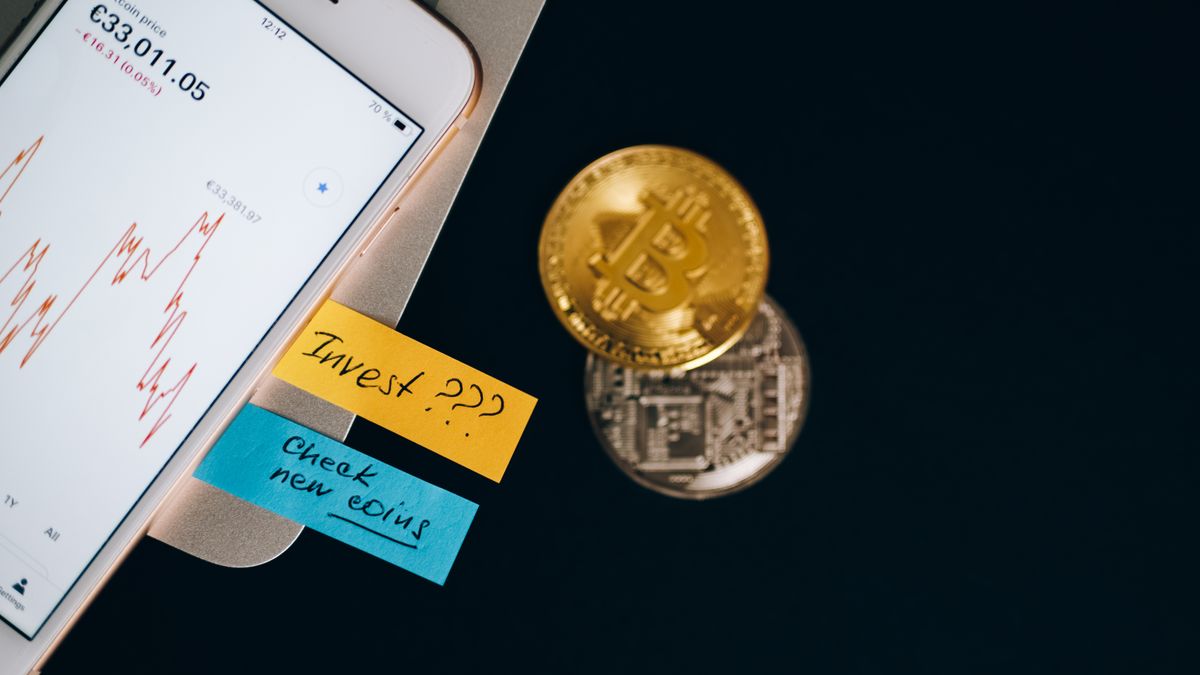Bitcoin coins and smartphone displaying price chart with investment notes.