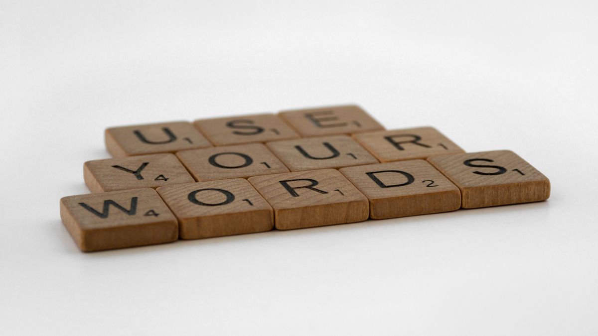 Close-up of wooden letter tiles spelling 'Use Your Words' on a white background, perfect for communication and language themes.