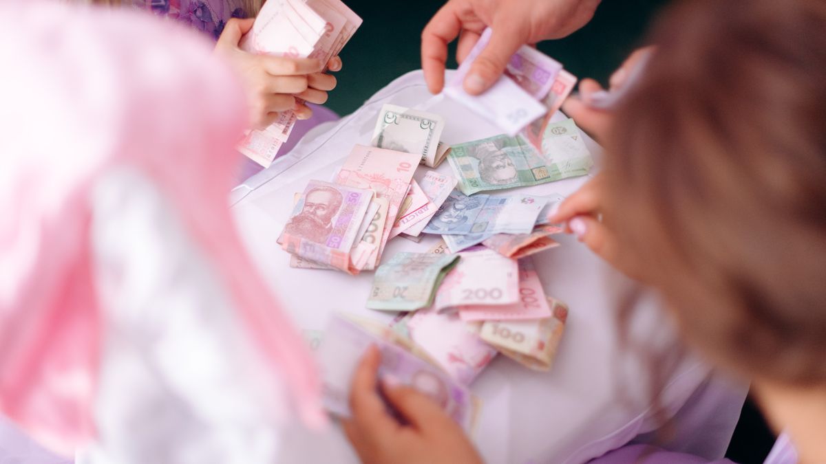 A child and adult hands sorting colorful banknotes on a table, symbolizing financial education.