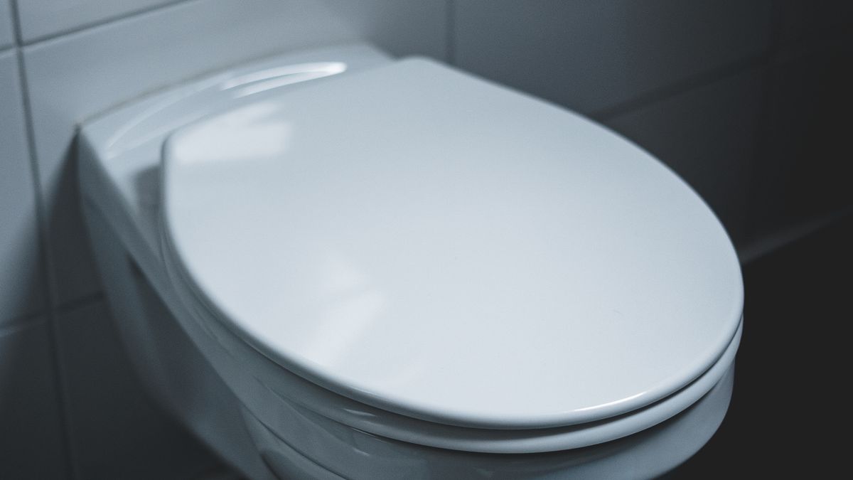 A sleek and modern white toilet in a well-lit minimalist bathroom setting.