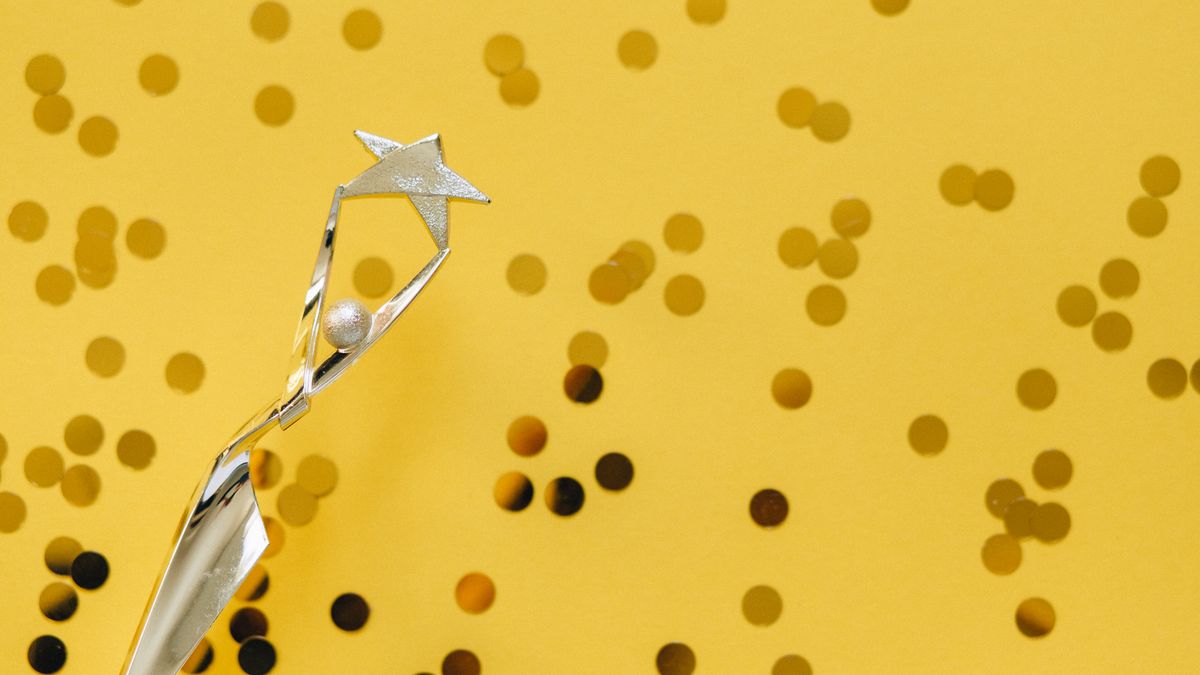 A silver trophy with a star design on a vibrant yellow background adorned with confetti.
