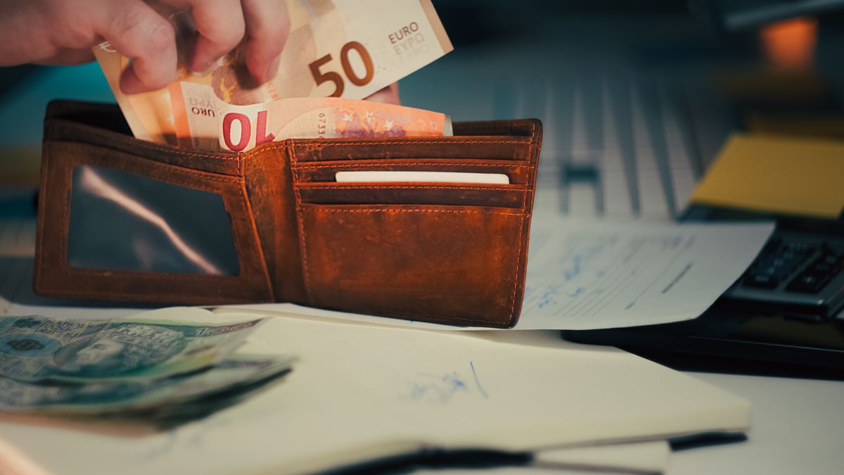 A wallet with euro banknotes and documents on an office desk, symbolizing finance and budgeting.