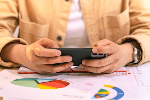 A business professional using a smartphone to analyze charts and graphs, likely for work.