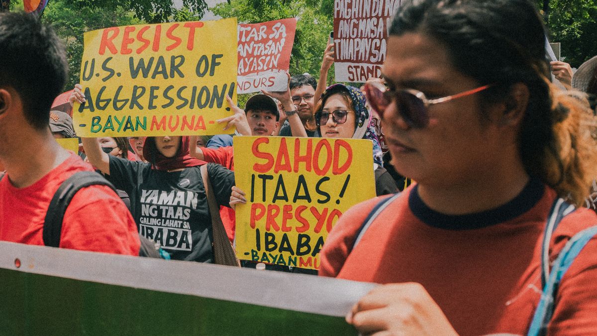 A vibrant protest in Metro Manila with people holding banners against US policies.
