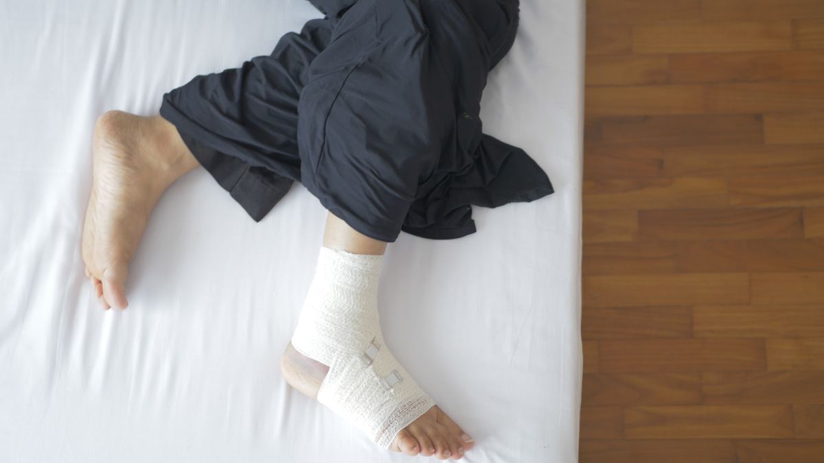 Top view of a bandaged foot resting on a bed, depicting injury and recovery.