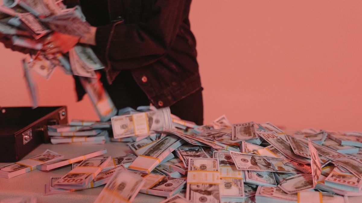 Bundles of US dollar bills on a table with a person organizing them.