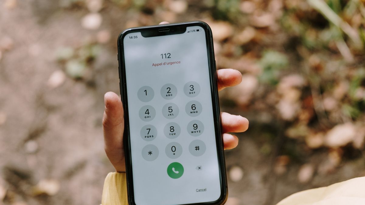 Close-up of emergency number dialed on smartphone held outdoors, emphasizing mobile technology's role in safety.