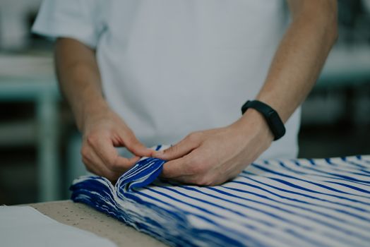 Close-up of hands holding striped fabric indoors, highlighting textile details.
