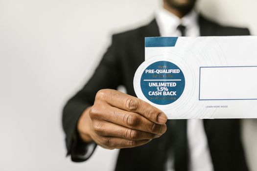 Close-up of a businessman holding an envelope with a pre-qualified cash back offer.