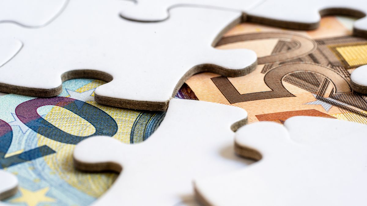 Close-up of euro banknotes revealed under puzzle pieces, symbolizing financial solutions.