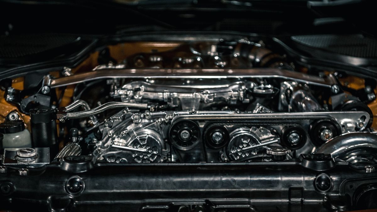 From above of polished stainless engine and automobile apparatuses under hood of new car