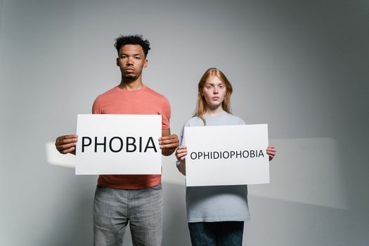 Portrait of people holding signs about phobias and ophidiophobia.