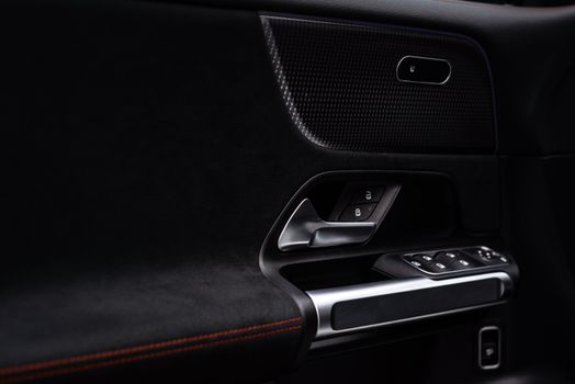 Close-up view of a modern car door panel with handle and electronic controls.