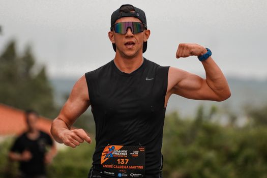 Runner flexes muscles triumphantly during an outdoor marathon event.