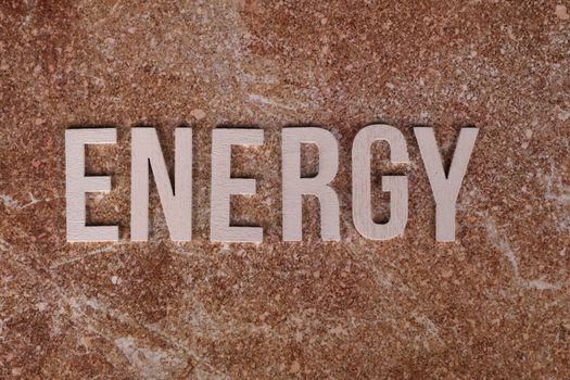 Word 'Energy' on natural stone texture, symbolizing raw power.