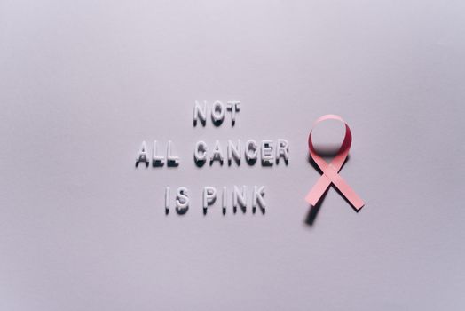 Pink ribbon highlighting diverse cancer awareness on a white surface.