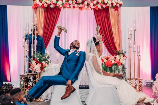 Bride and groom enjoying the fun shoe game at a colorful wedding ceremony.