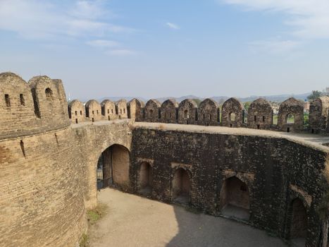 Aerial view of a historic medieval stone fortress with arched wall structures under a clear sky.